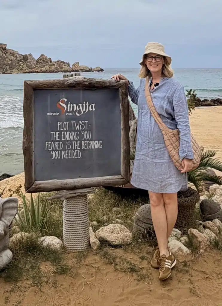 author Dee Andrews in front of sign about writing in Malta